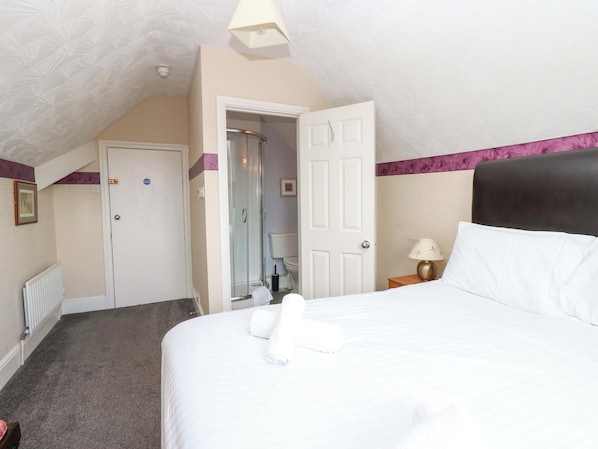 A hotel room with a bed, a bathroom, and a door leading to another room. - Fern Lee (Carlisle)