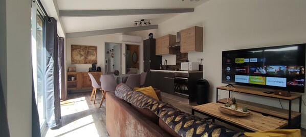 A modern living room with a sofa, a TV, and a wooden dining table.