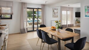 A modern dining area with a wooden table, black chairs, and a view of an outdoor pool. - Villa Roti in Roti  - Haus für 8 Personen (Kostrcani)