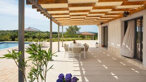 A covered outdoor patio with a pool, a table with chairs, and a view of the surrounding landscape. - Villa Roti in Roti  - Haus für 8 Personen (Kostrcani)