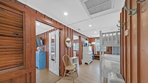 Een kamer met houten lambrisering, een stapelbed, een bureau met stoel, een dressoir en een spiegel aan de muur.