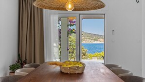 A dining area with a wooden table, wicker basket with lemons, and a view of the sea. - Stylish and luxurious beachfront villa Larisa with private pool and Whirlpool (Rogoznica)
