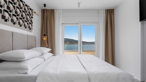 A hotel room with a large bed, a view of the sea, and a wall-mounted TV. - Stylish and luxurious beachfront villa Larisa with private pool and Whirlpool (Rogoznica)