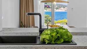 A kitchen with a sink, a large window with a view of the sea, and a potted plant. - Stylish and luxurious beachfront villa Larisa with private pool and Whirlpool (Rogoznica)