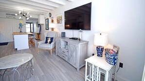A modern kitchen with a coffee station, a dining area with a round table, and a living area with a TV and seating. - Jada 2b 1 Bedroom Condo by RedAwning (Ocean City)