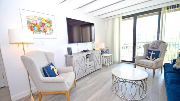 A modern living room with a flat-screen TV, two armchairs, a round coffee table, and a small side table. - Jada 2b 1 Bedroom Condo by RedAwning (Ocean City)