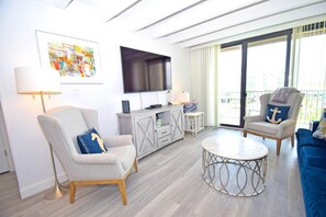 A modern living room with a flat-screen TV, two armchairs, a round coffee table, and a small side table. - Jada 2b 1 Bedroom Condo by RedAwning (Ocean City)