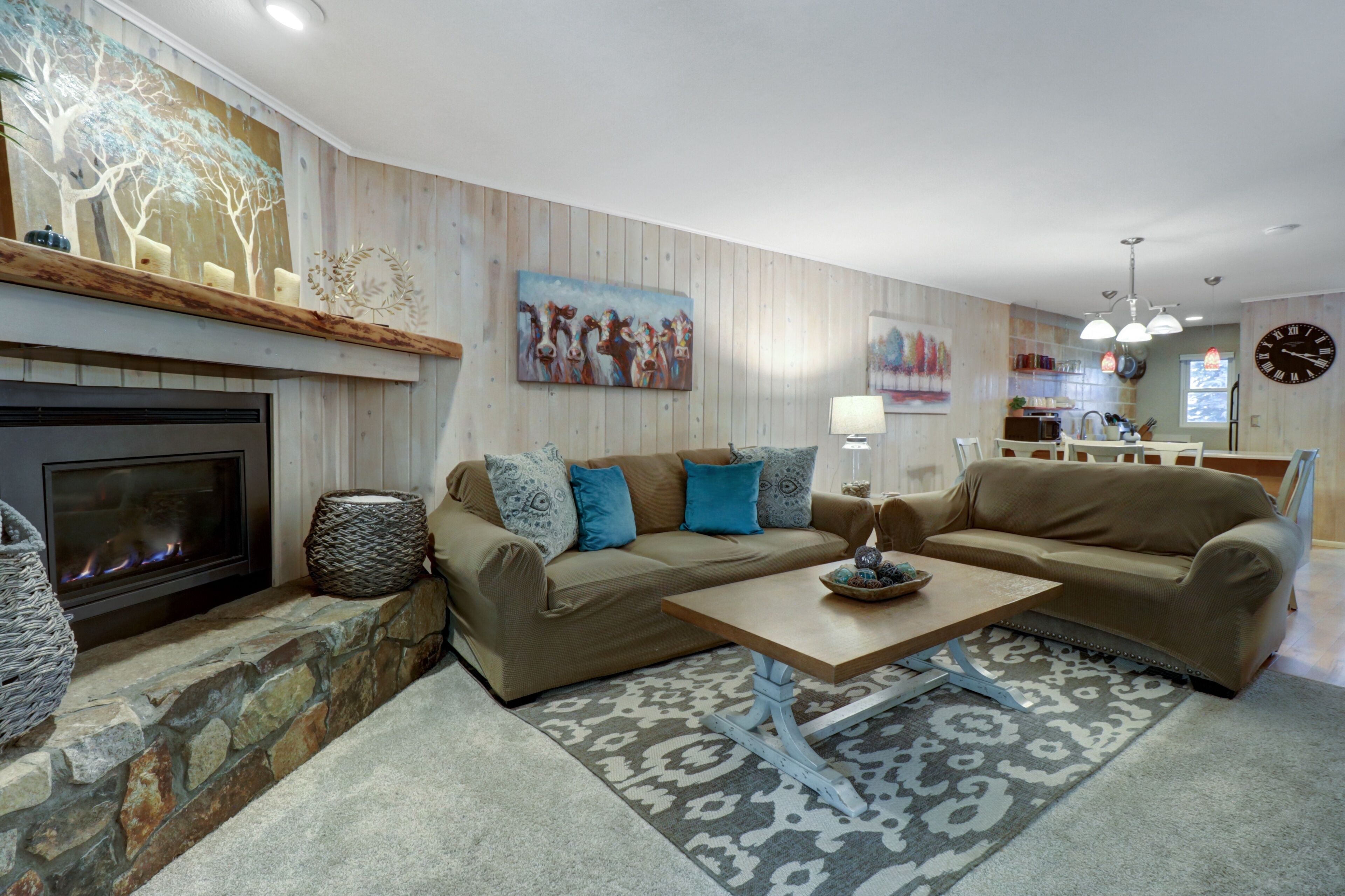 A modern living room with a fireplace, a sofa set, a coffee table, and a kitchen area in the background.
