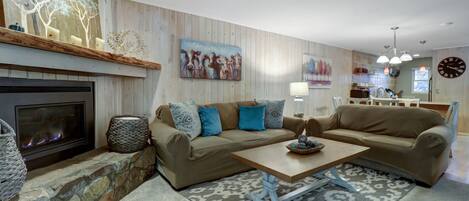 A modern living room with a fireplace, a sofa set, a coffee table, and a kitchen area in the background.