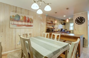 Enjoy meals with family and friends at the dining table for six, surrounded by a beautiful painting of trees.