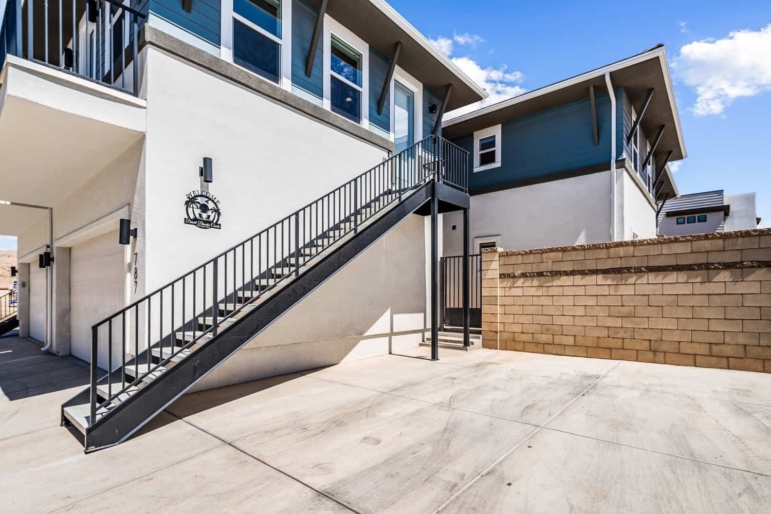 A modern building with a staircase leading to a covered entrance, a brick wall, and a clear sky.