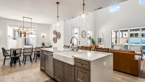 A modern kitchen with a large island, dark cabinetry, and pendant lighting. - Desert Brooke Villa 6 Bedroom Townhouse (St. George)