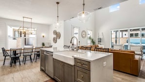 A modern kitchen with a large island, dark cabinetry, and pendant lighting. - Desert Brooke 5 Bedroom Townhouse (St. George)