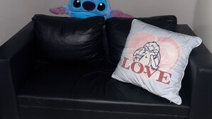 Ein schwarzes Sofa mit einem Kissen, das einen Comic-Charakter und das Wort 'LOVE' zeigt.