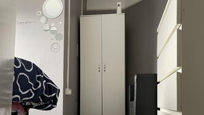 Ein Flur mit einem Kleiderschrank, einem kleinen Kühlschrank und einer Wand mit runden Verzierungen.