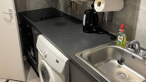 Eine kleine Küche mit Waschmaschine, Kaffeemaschine und Spüle.