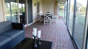 Ein überdachter Patio-Bereich mit einer Couch, einem Tisch und Stühlen. Auf einem Tisch stehen zwei Kerzen.