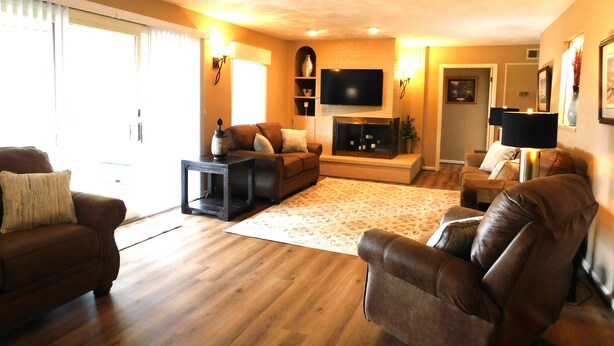 Ein Wohnzimmer mit Holzboden, Ledersofas, einem Flachbildfernseher und einem Kamin.