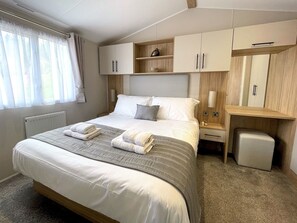 Ein ordentlich eingerichtetes Schlafzimmer mit einem großen Bett, Nachttischen, einem Kleiderschrank und einer kleinen Sitzecke.
