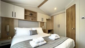 Ein modernes Hotelzimmer mit einem großen Bett, eingebautem Kleiderschrank und einer kleinen Ablagefläche mit einem Dekorationsobjekt.