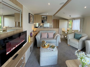 Ein kompakter Wohnbereich mit Sofa, Hocker und Fernseher.