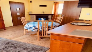 Un coin repas avec une table dressée pour deux personnes, une cheminée et un téléviseur fixé au mur.