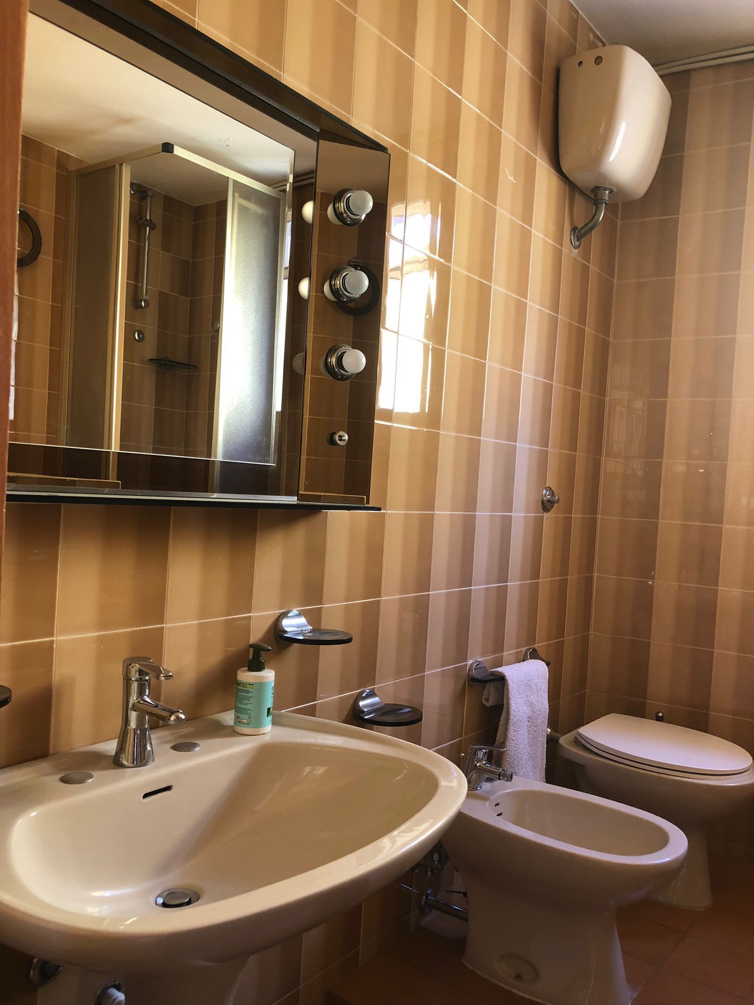 A bathroom with a sink, mirror, toilet, and bidet.