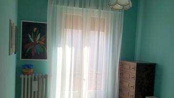 Una camera da letto con un letto, un termosifone, una cassettiera e un quadro appeso al muro.