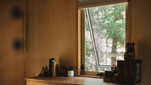 Un aparador de madera con una ventana, una planta pequeña y algunos libros.