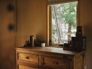 A wooden dresser with a window, a small plant, and a few books. - Pike National Forest Cabin with Mountain Views, Deck & Wood Fireplace (Woodland Park)