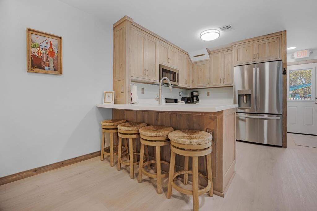 Eine Küche mit Holzausstattung, einem Edelstahlkühlschrank und einer Bar mit Sitzgelegenheit.