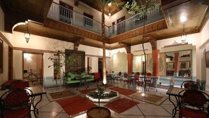 A spacious atrium with a central fountain, multiple seating areas, and a balcony with ornate railings. - Marrakech (Marrakech)