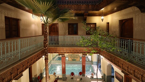 A courtyard with a pool, ornate railings, and a palm tree. - Marrakech (Marrakech)