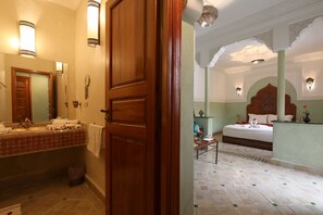 Une salle de bain d’hôtel avec une porte en bois, un miroir et un lavabo avec des serviettes.