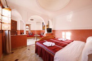 Une chambre d’hôtel avec un grand lit, une télévision, un canapé et une petite table.