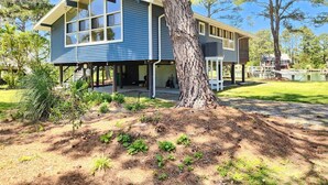A two-story house with a large window, a tree in front, and a clear sky.