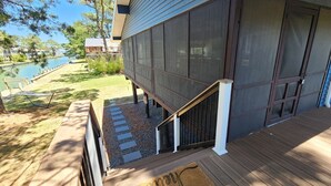 A modern house with a deck, a staircase, and a view of a lake.