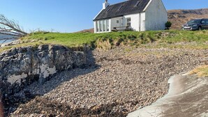 A white house with a sloped roof, a stone wall, and a gravel path. - The House on the Point - UK43807 (Kylerhea)