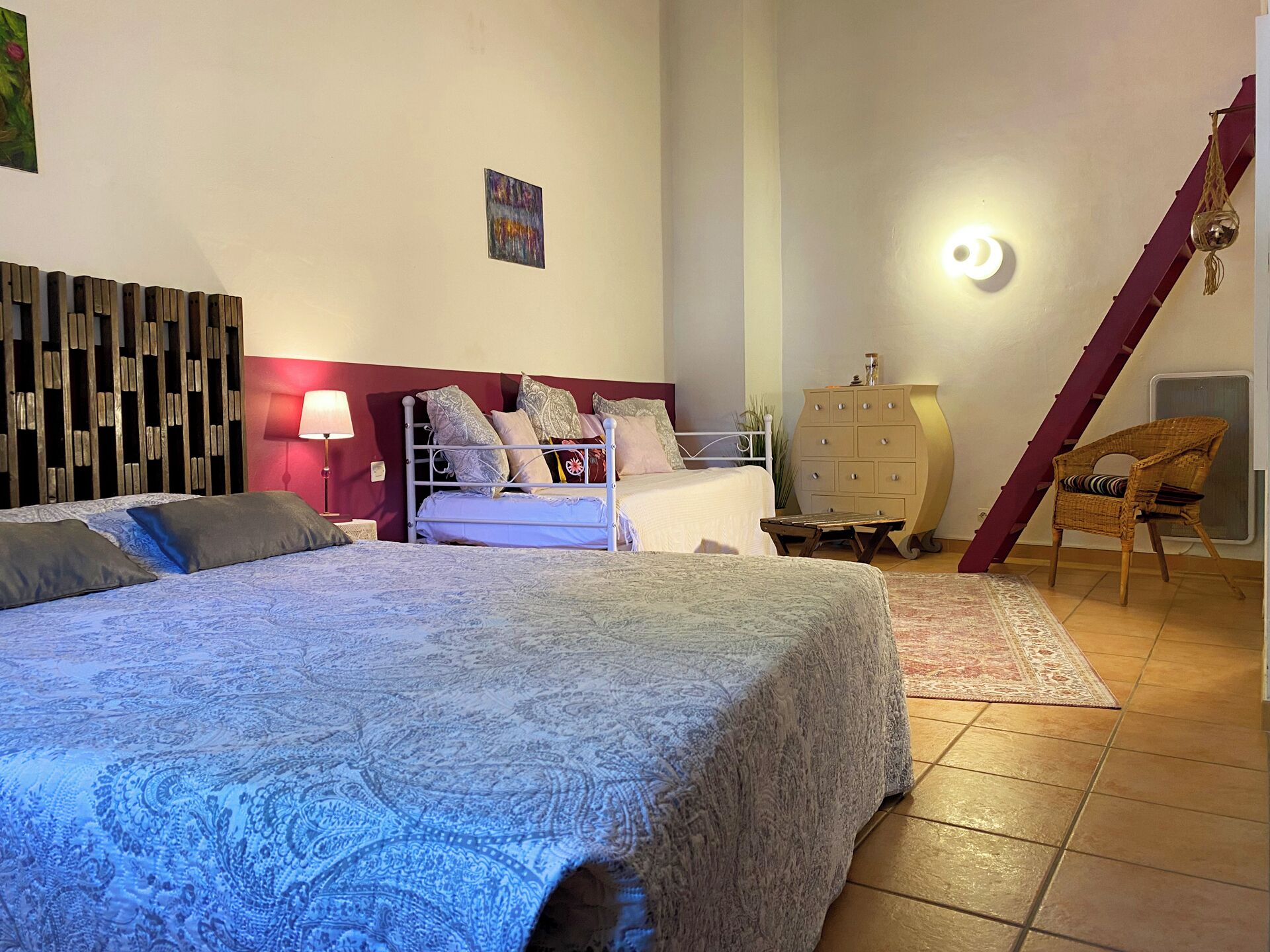 Une chambre à coucher avec un grand lit, une commode, une chaise et un escalier.