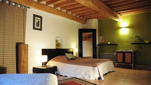 A bedroom with a wooden ceiling, a bed with a white bedspread, a nightstand with a lamp, a small table with a vase, and a green wall with a light fixture. - Orangerie de Cardet B&B (Cardet)