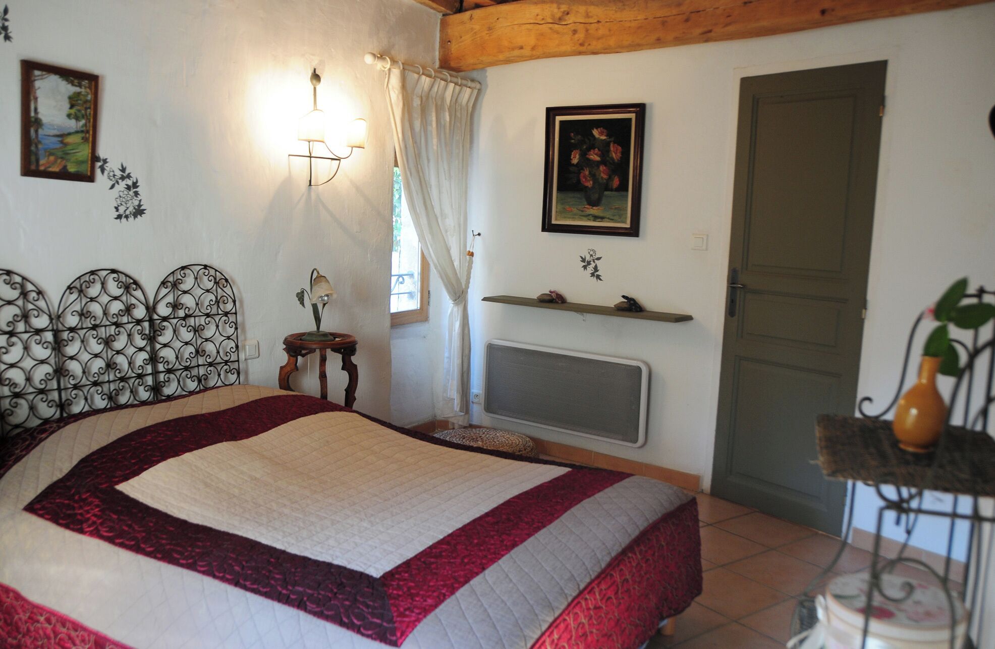 Un dormitorio con cama, un radiador, una puerta y una mesita con lámpara.