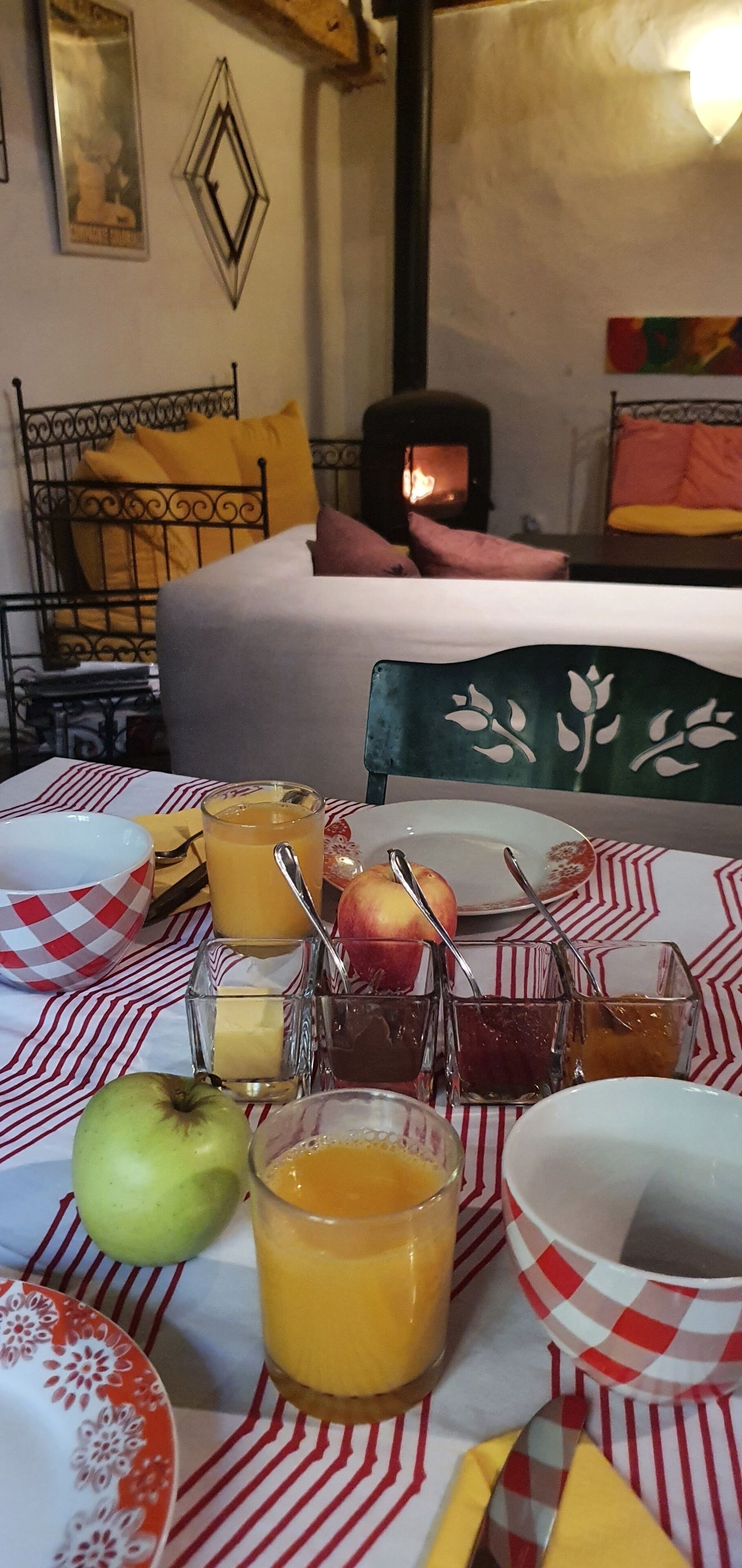 Een ontbijttafel met fruit, sappen en toevoegingen, een bed met kussens, en een haard op de achtergrond.