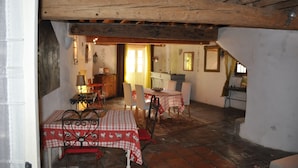 A rustic interior with exposed wooden beams, a dining area with checkered tablecloths, and a cozy atmosphere. - Orangerie de Cardet B&B (Cardet)