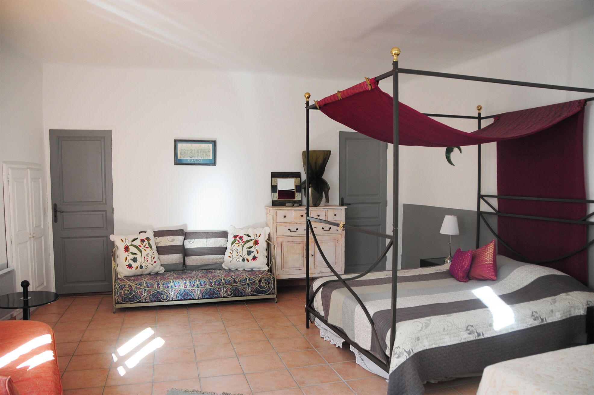 Un dormitorio con cama con dosel, sofá cama, cómoda y una puerta.