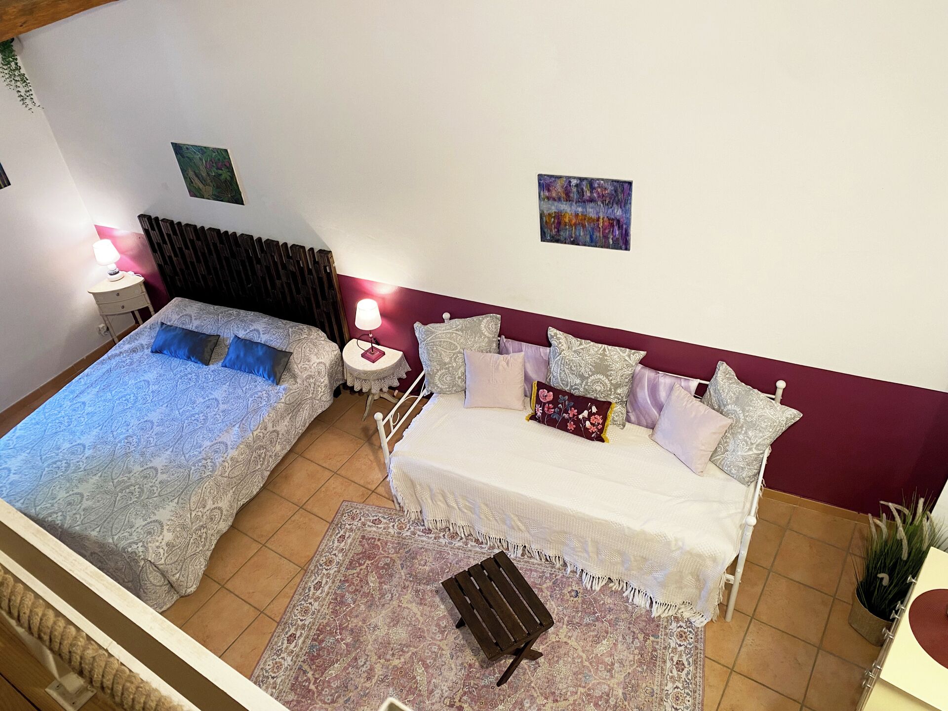 A bedroom with two beds, a nightstand, a lamp, a small table, and a rug.
