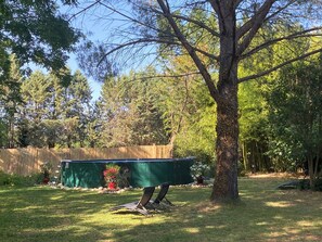 A backyard with a green table, two chairs, a tree, and a wooden fence. - Orangerie de Cardet B&B (Cardet)