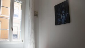 A bedroom with a bed, a window with curtains, and a painting on the wall. - Testaccio Piramide by Interhome (Rome: Historical City Center)