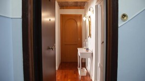 A hallway with wooden flooring, a white door, and a small white table with a mirror and wall-mounted lights. - Testaccio Piramide by Interhome (Rome: Historical City Center)