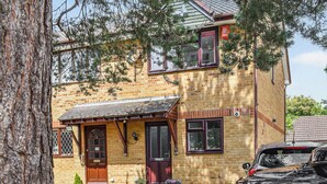 A two-story brick house with a front porch, a garage, and a parked car. - 2 bedroom accommodation in Wareham (Wareham)