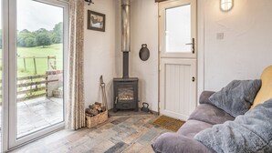 Een gezellige woonkamer met een open haard, een schuifpui naar een terras en een comfortabele bank.